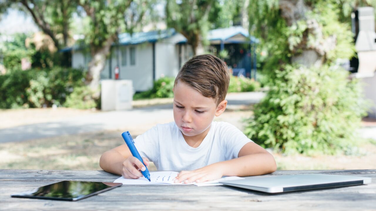 Boy drawing with pen in notebook