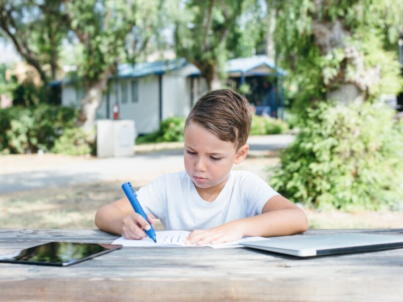 Boy drawing with pen in notebook