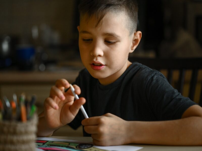 A 10-year-old boy draws a drawing with colored pencils