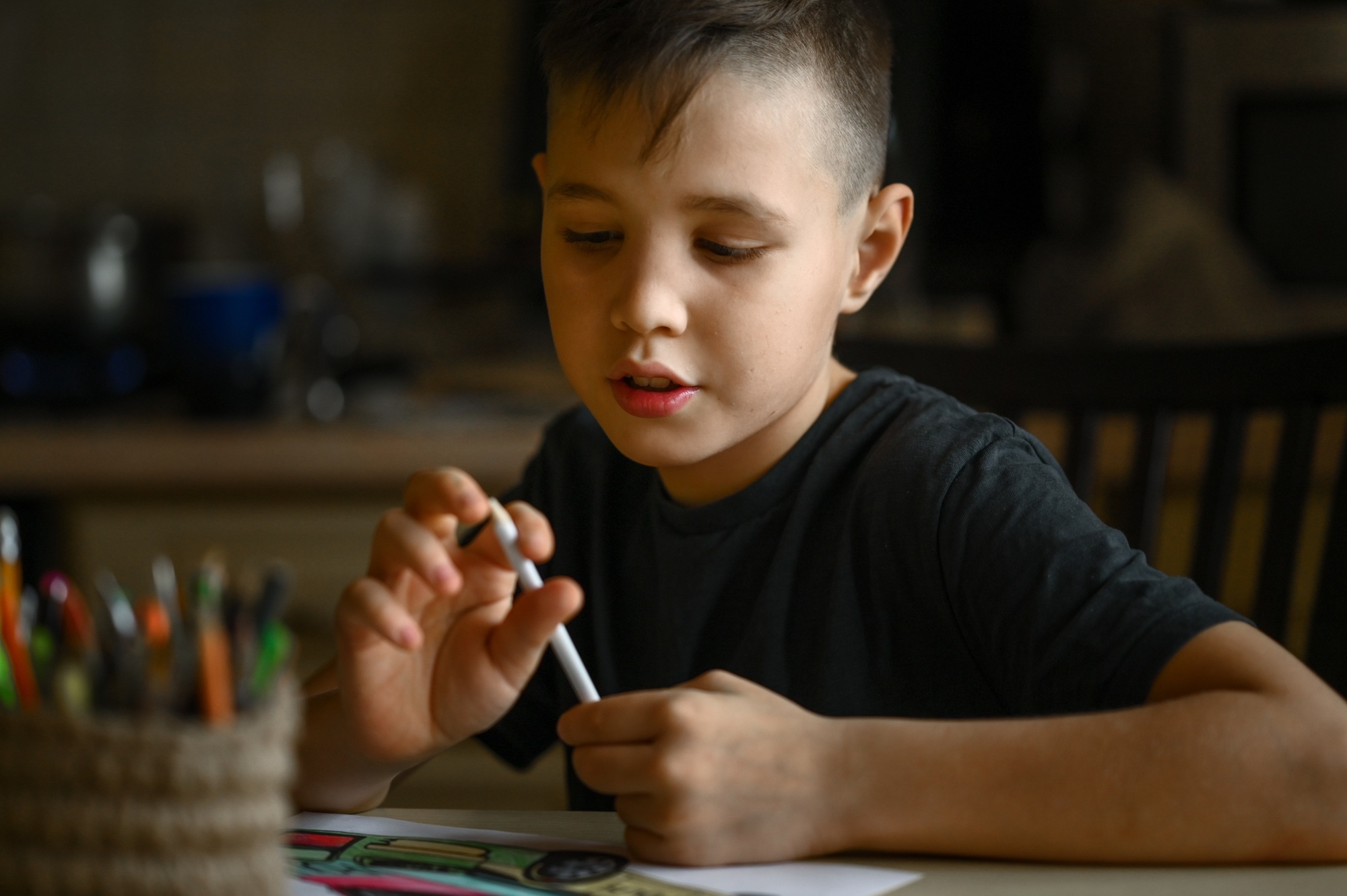 A 10-year-old boy draws a drawing with colored pencils
