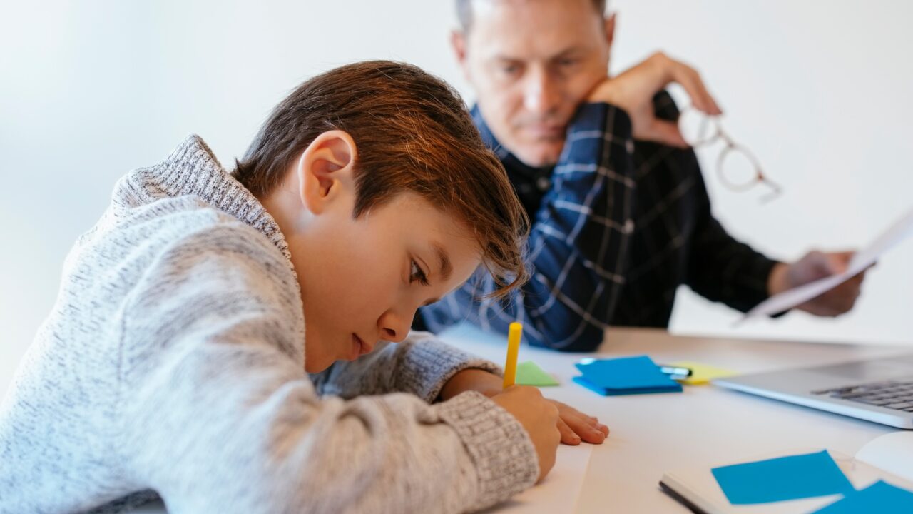 Businessman at desk in office looking at son drawing