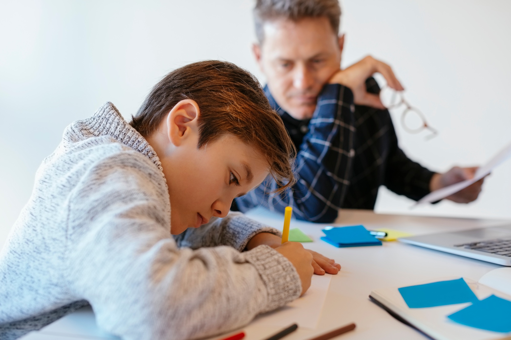 Businessman at desk in office looking at son drawing