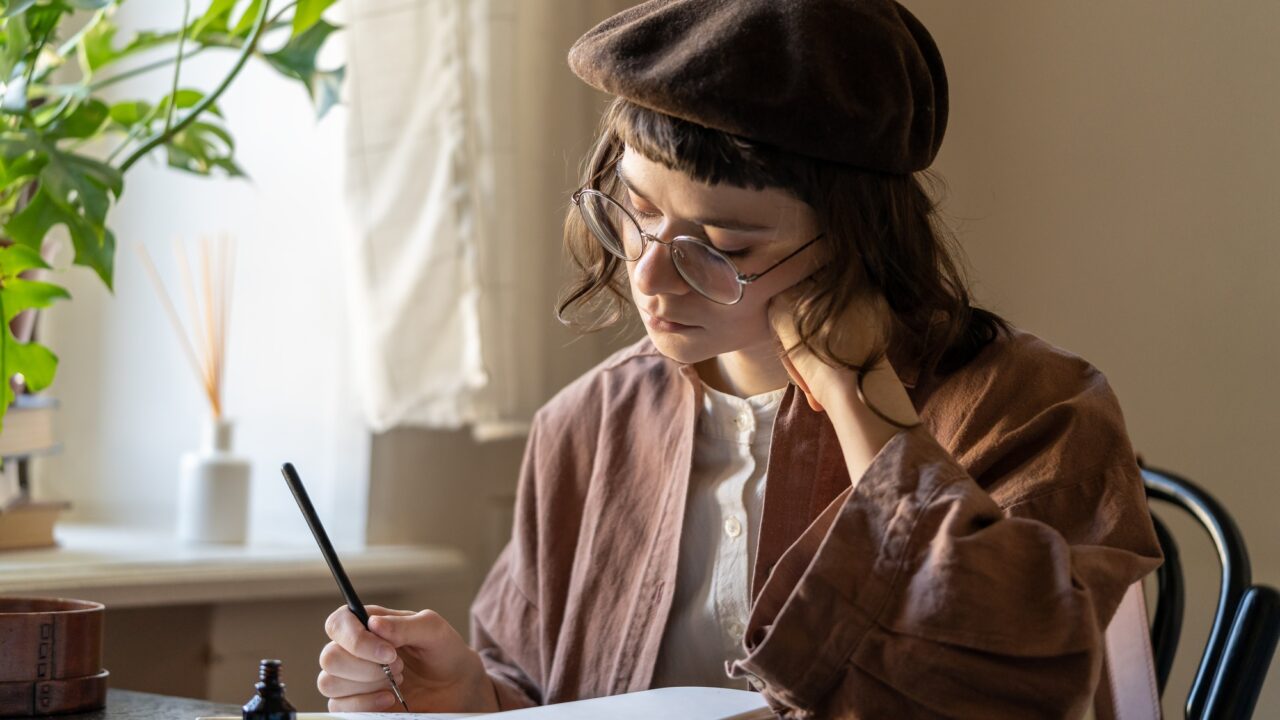Concentrated artist young woman drawing in notebook with black ink. Art therapy for stress relief