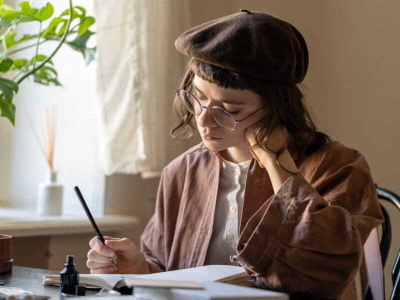 Concentrated artist young woman drawing in notebook with black ink. Art therapy for stress relief