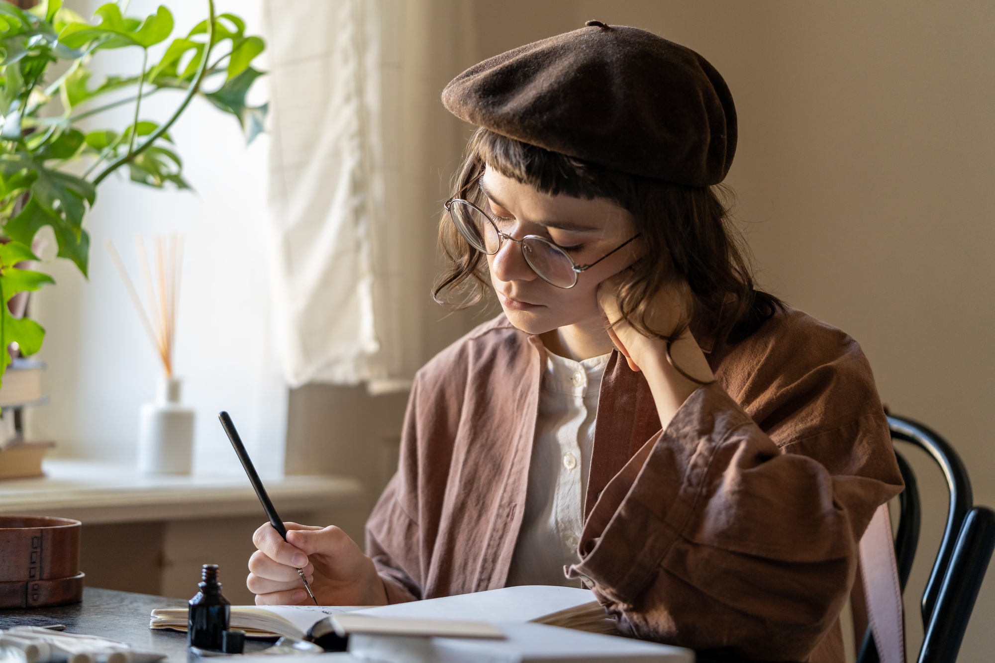 Concentrated artist young woman drawing in notebook with black ink. Art therapy for stress relief
