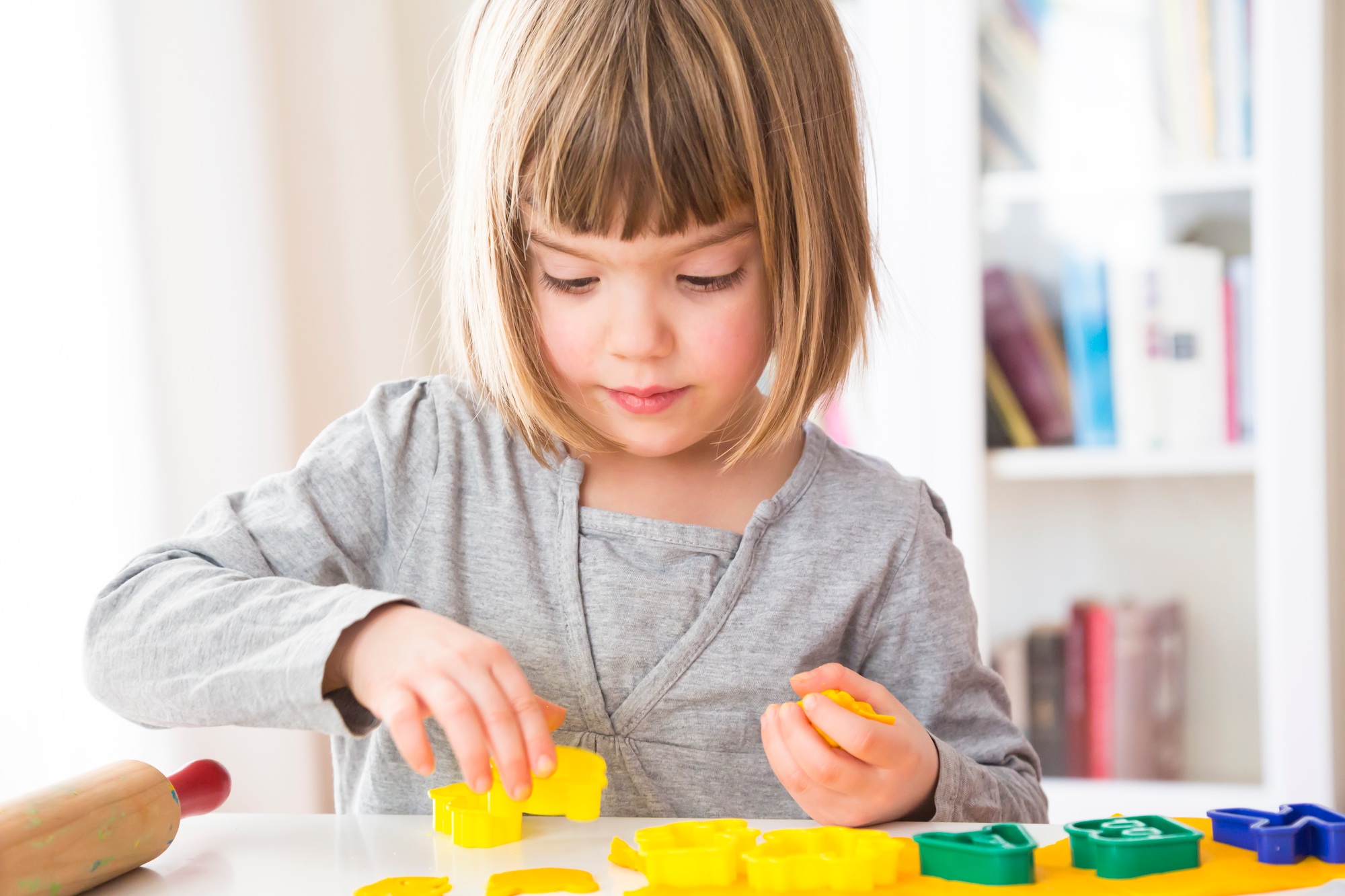 Little girl cutting out yellow modeling clay