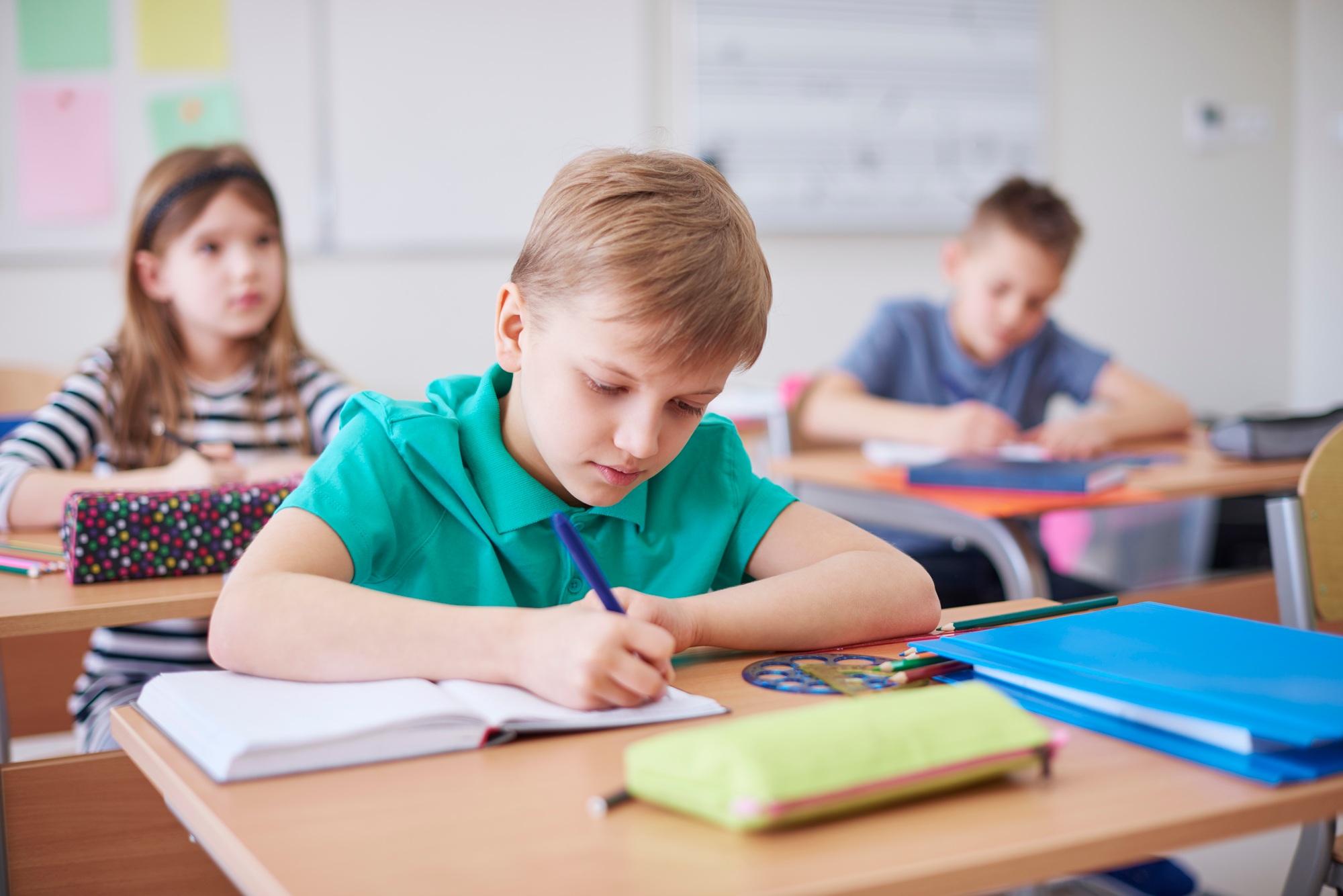 Schoolboy writing in exercise book in class