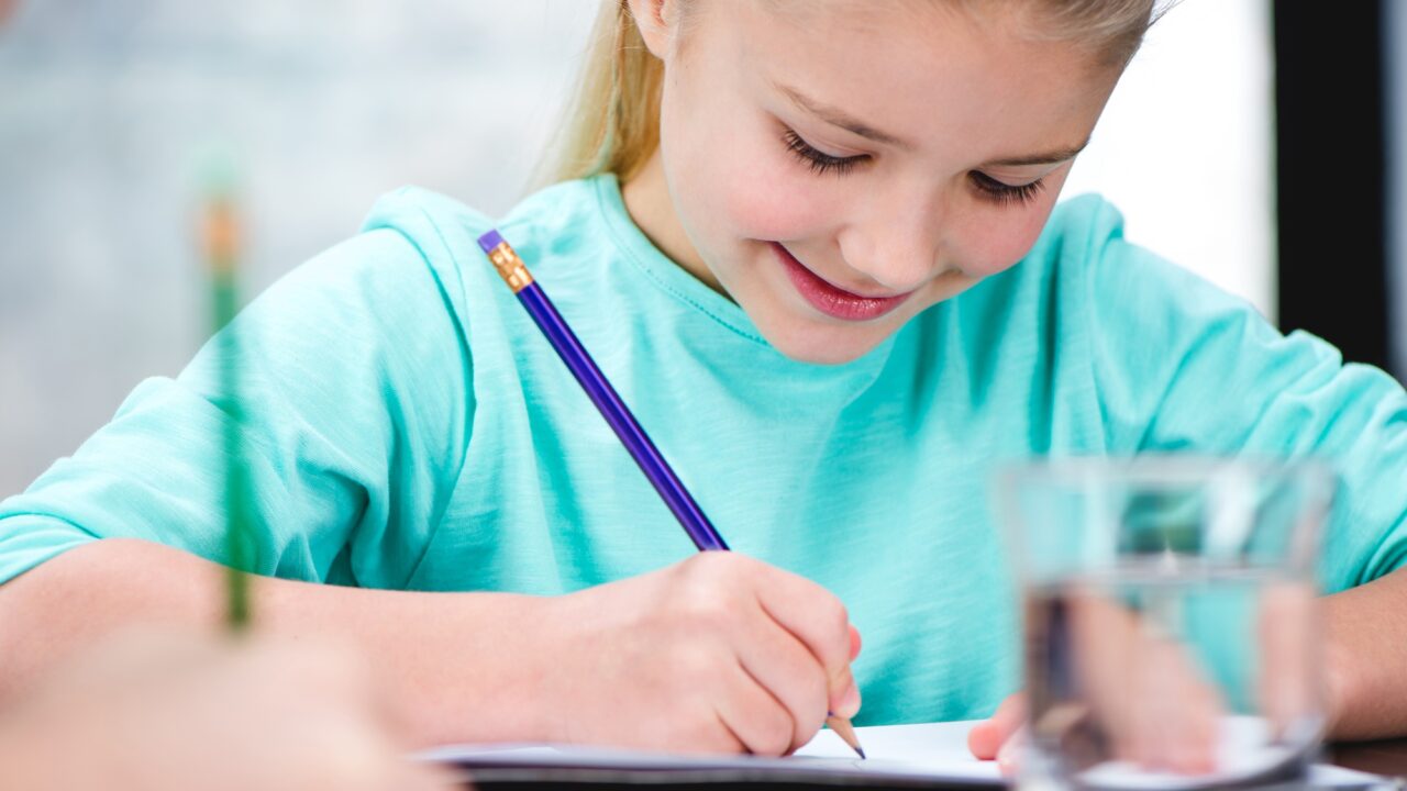 Smiling child drawing picture with pencil