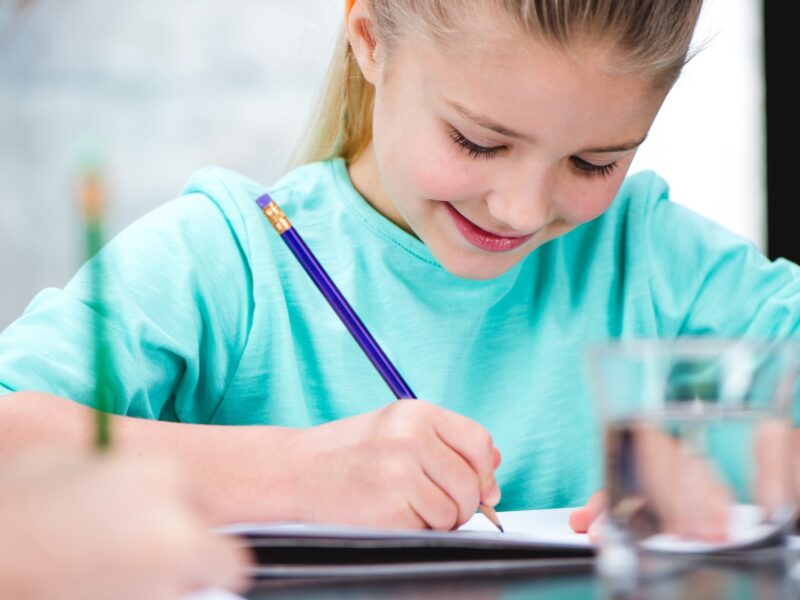 Smiling child drawing picture with pencil