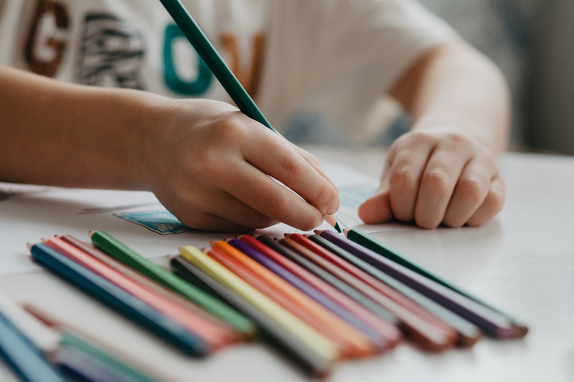 The boy draws with pencils at the kitchen, closeup