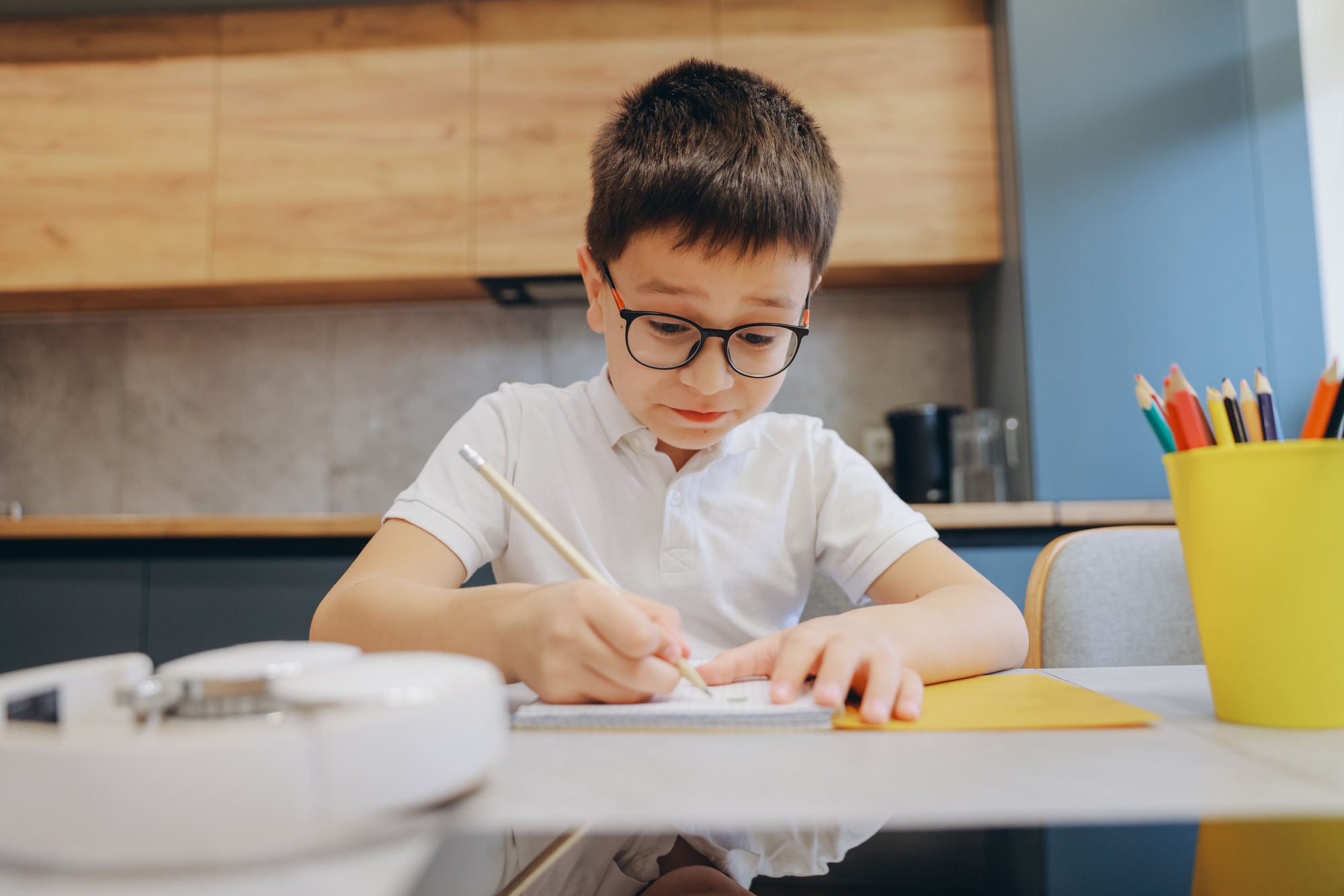 Concentrated boy drawing on notebook with pencil at home