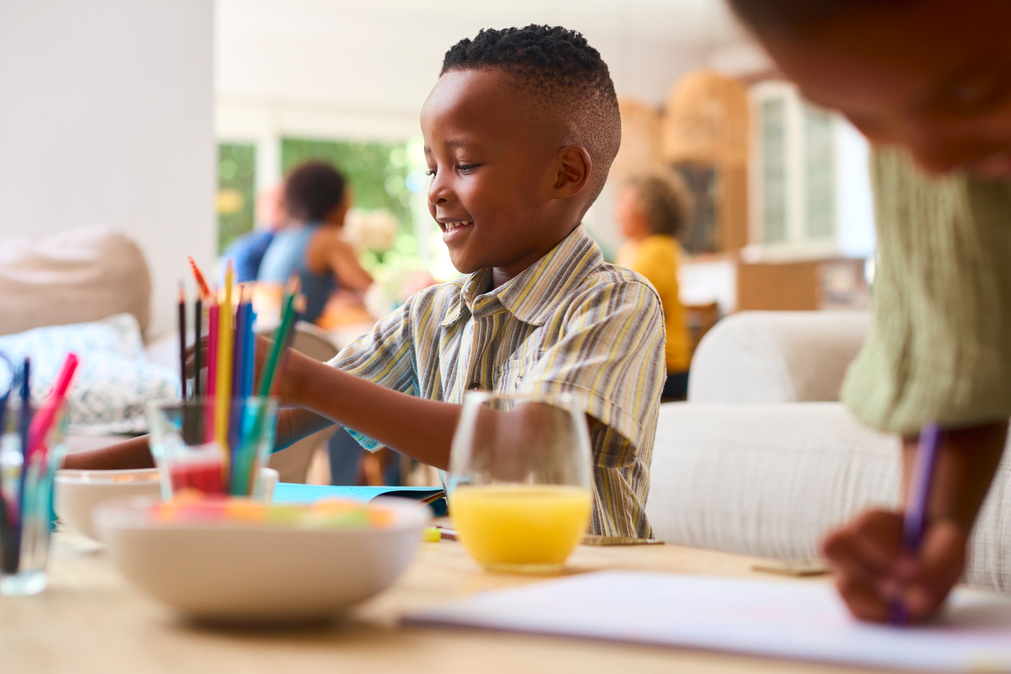 Grandchildren Indoors At Home Sitting At Table Drawing With Multi-Generation Family In Background
