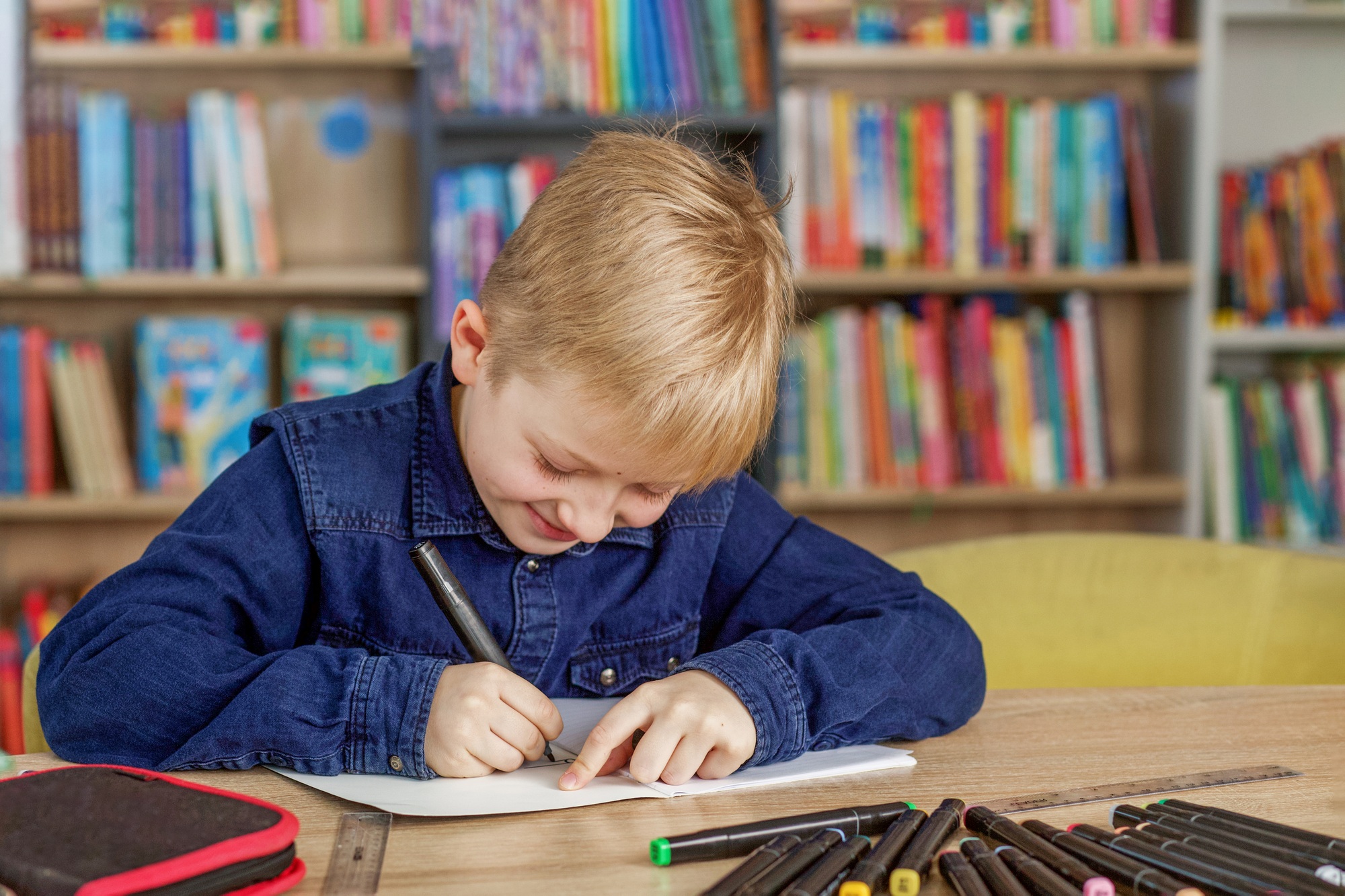 Child boy writes and draws in school or library. Bookstore concept, education and knowledge.