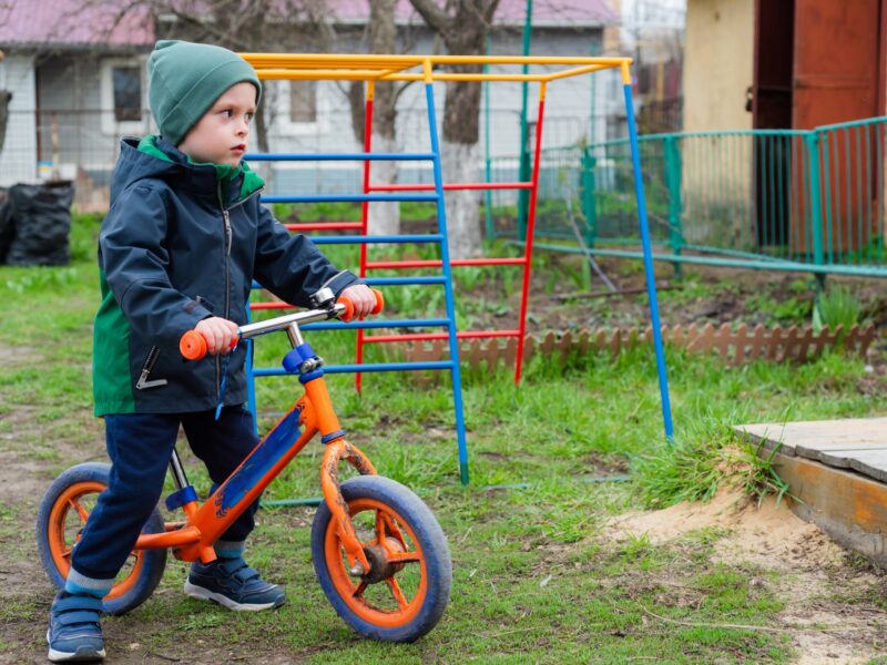 Child rides a balance bike outdoors in the garden
