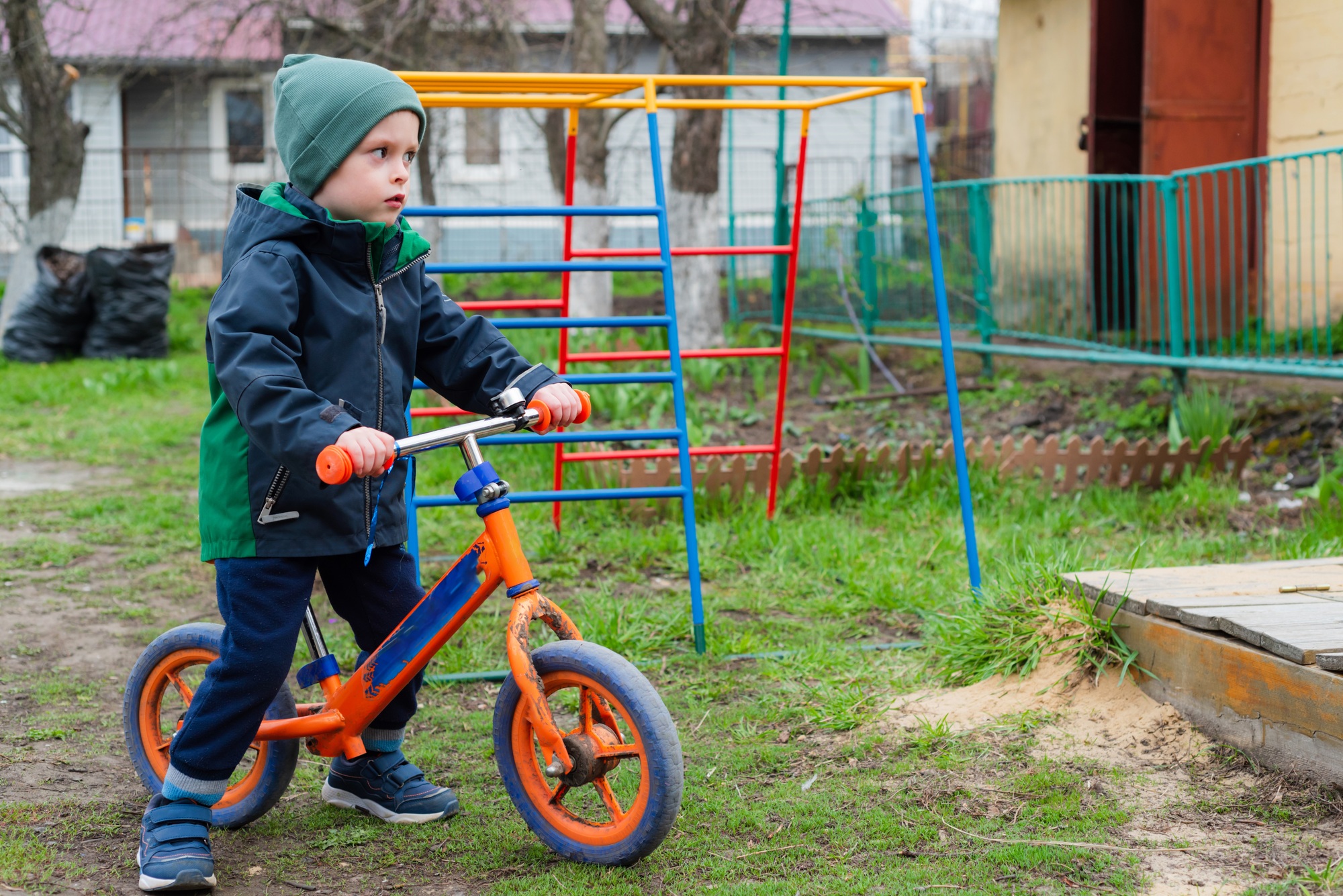 Child rides a balance bike outdoors in the garden