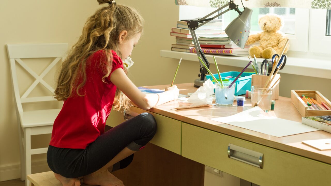 Girl child draws watercolor at the table at home