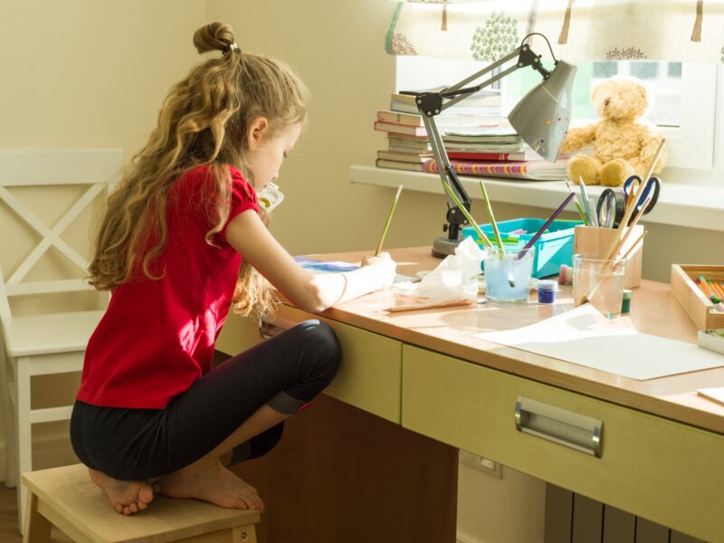 Girl child draws watercolor at the table at home