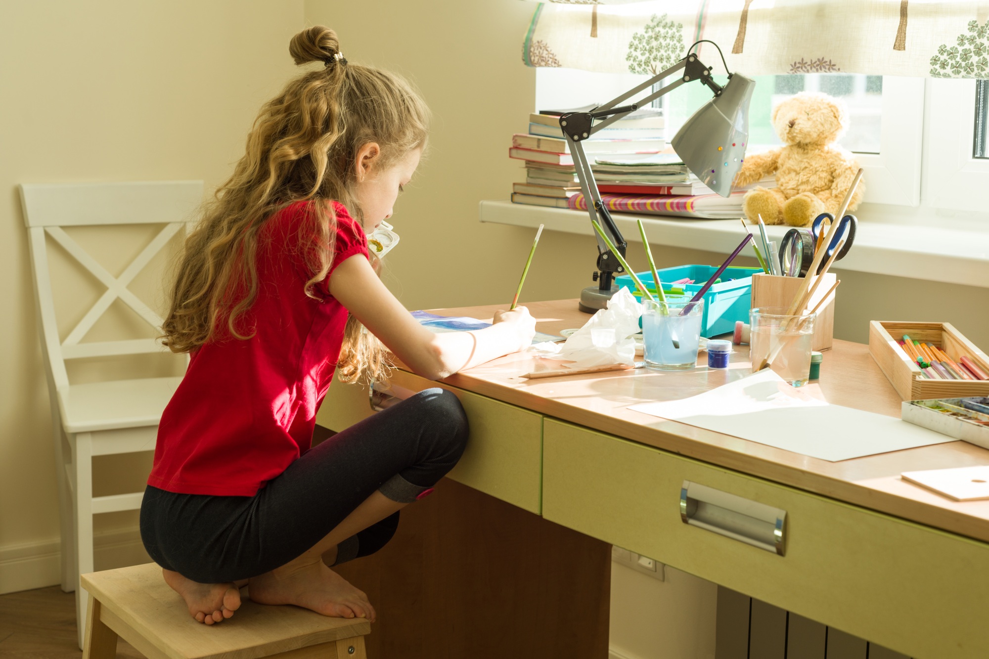 Girl child draws watercolor at the table at home