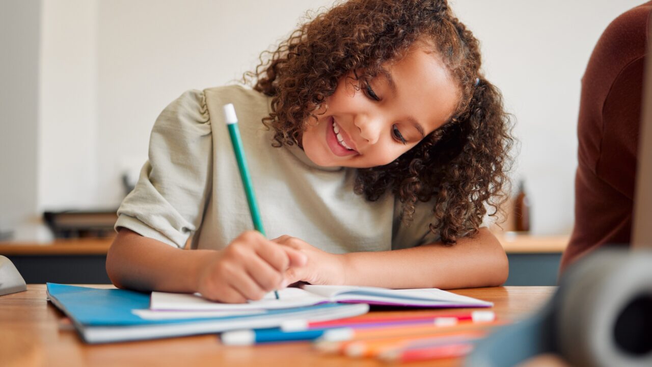 Learning, smiling and creative young girl drawing with a colorful pencil feeling happy and content.