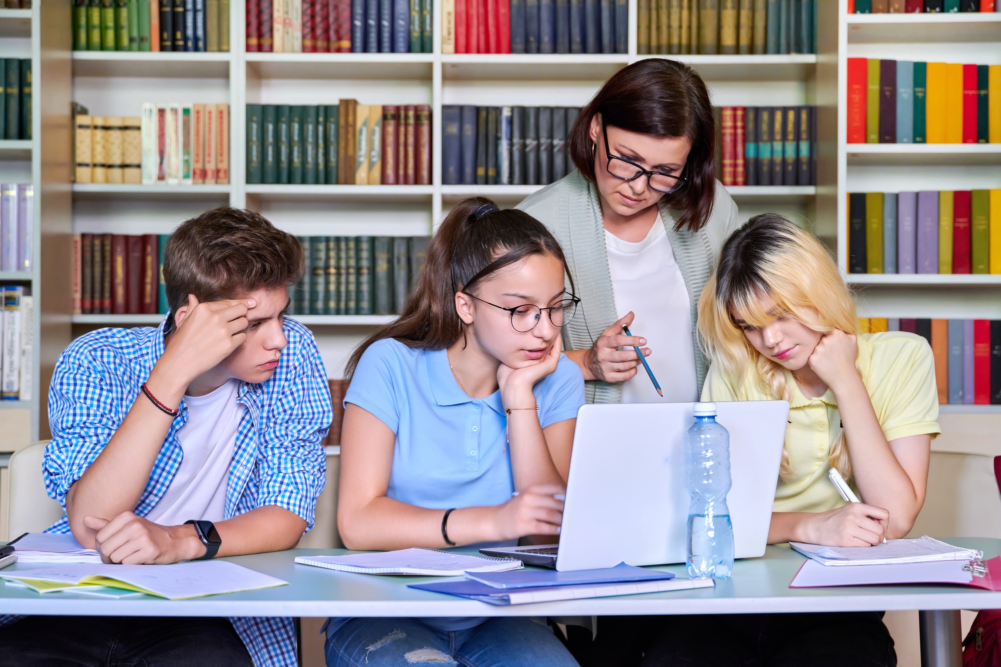 Lesson in library, high school teacher with group of teenagers