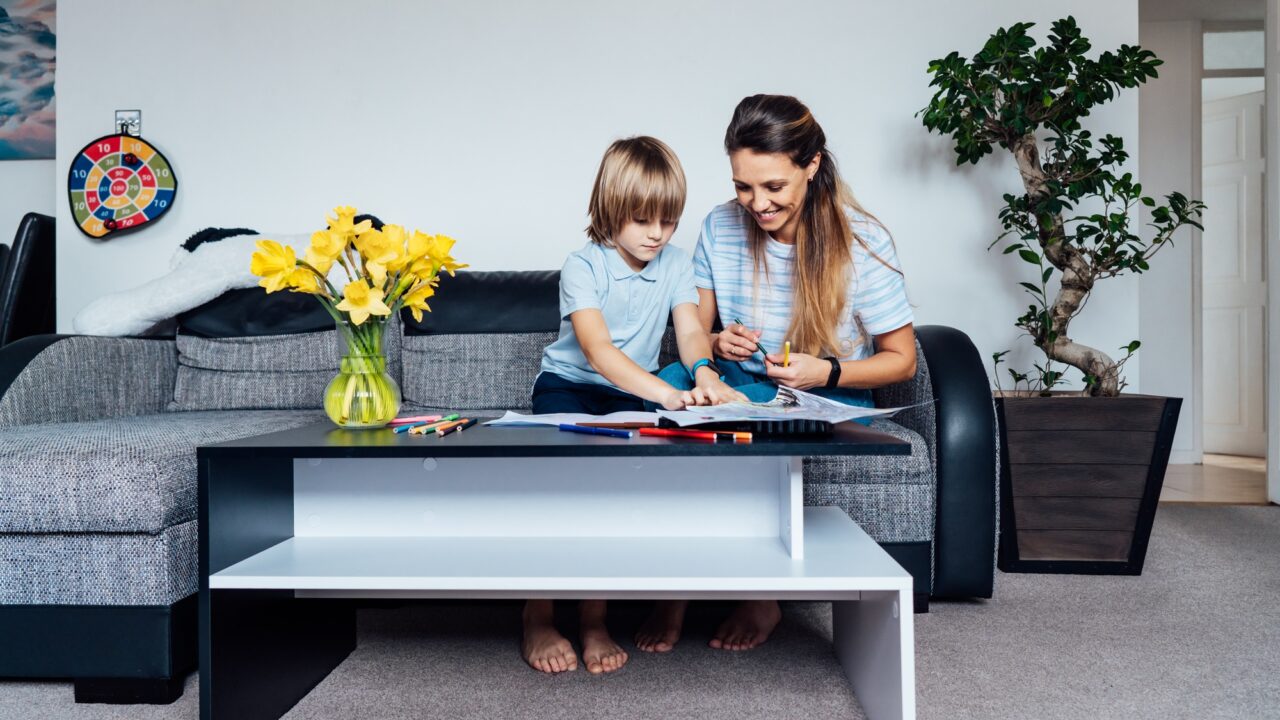 Mother and son drawing with color pencils and markers in the living room. Child creativity concept.