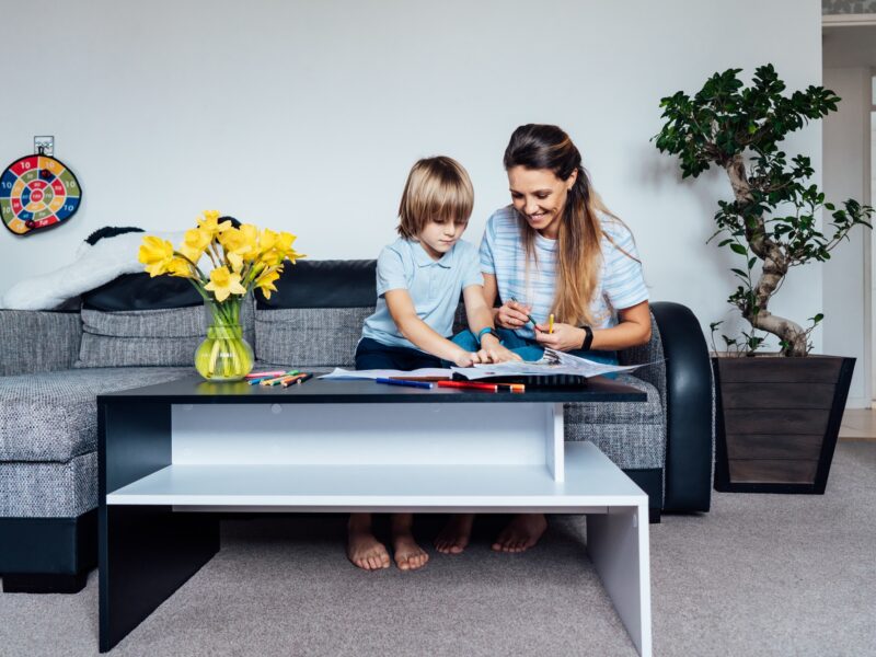 Mother and son drawing with color pencils and markers in the living room. Child creativity concept.