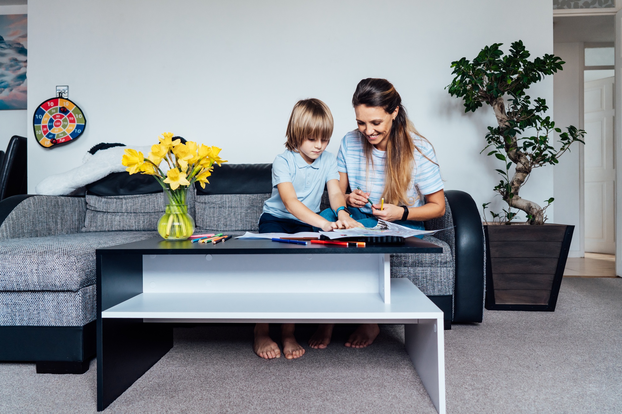 Mother and son drawing with color pencils and markers in the living room. Child creativity concept.