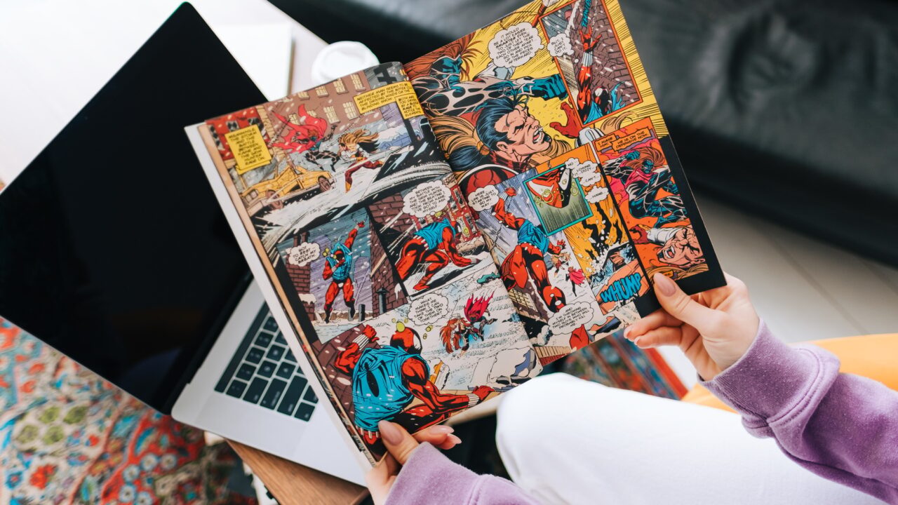 Person reading comic book at home in living room.