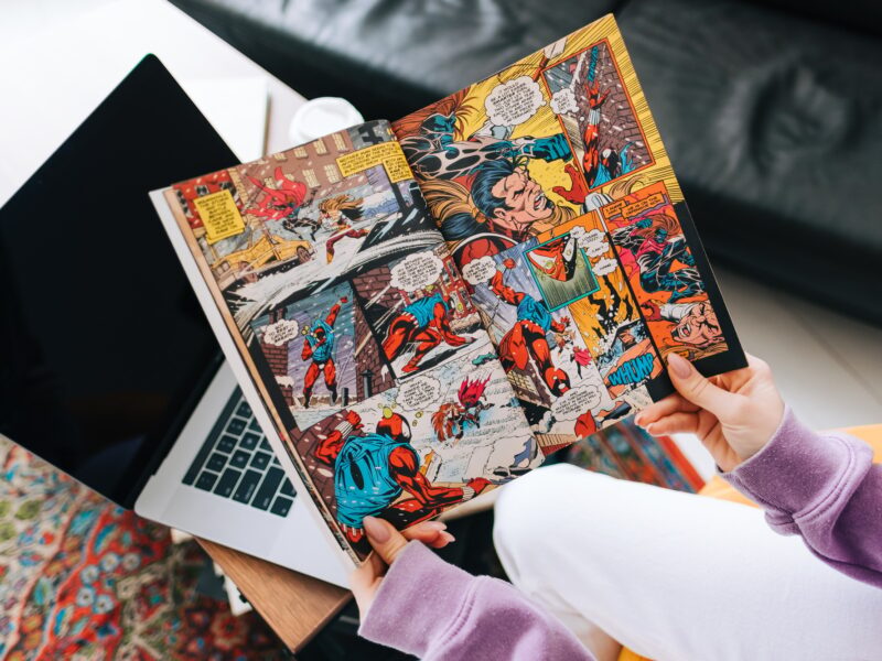 Person reading comic book at home in living room.