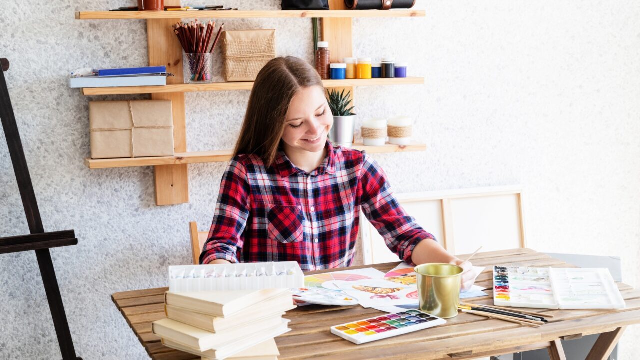 Smiling young woman drawing using watercolor