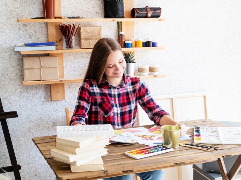 Smiling young woman drawing using watercolor