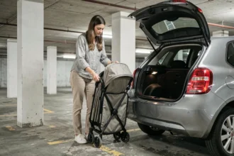 Maman repliant une poussette 4 en 1 compacte dans un coffre de petite voiture dans un parking urbain